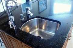Granite countertop with new stainless steel sink. Black with light specs.